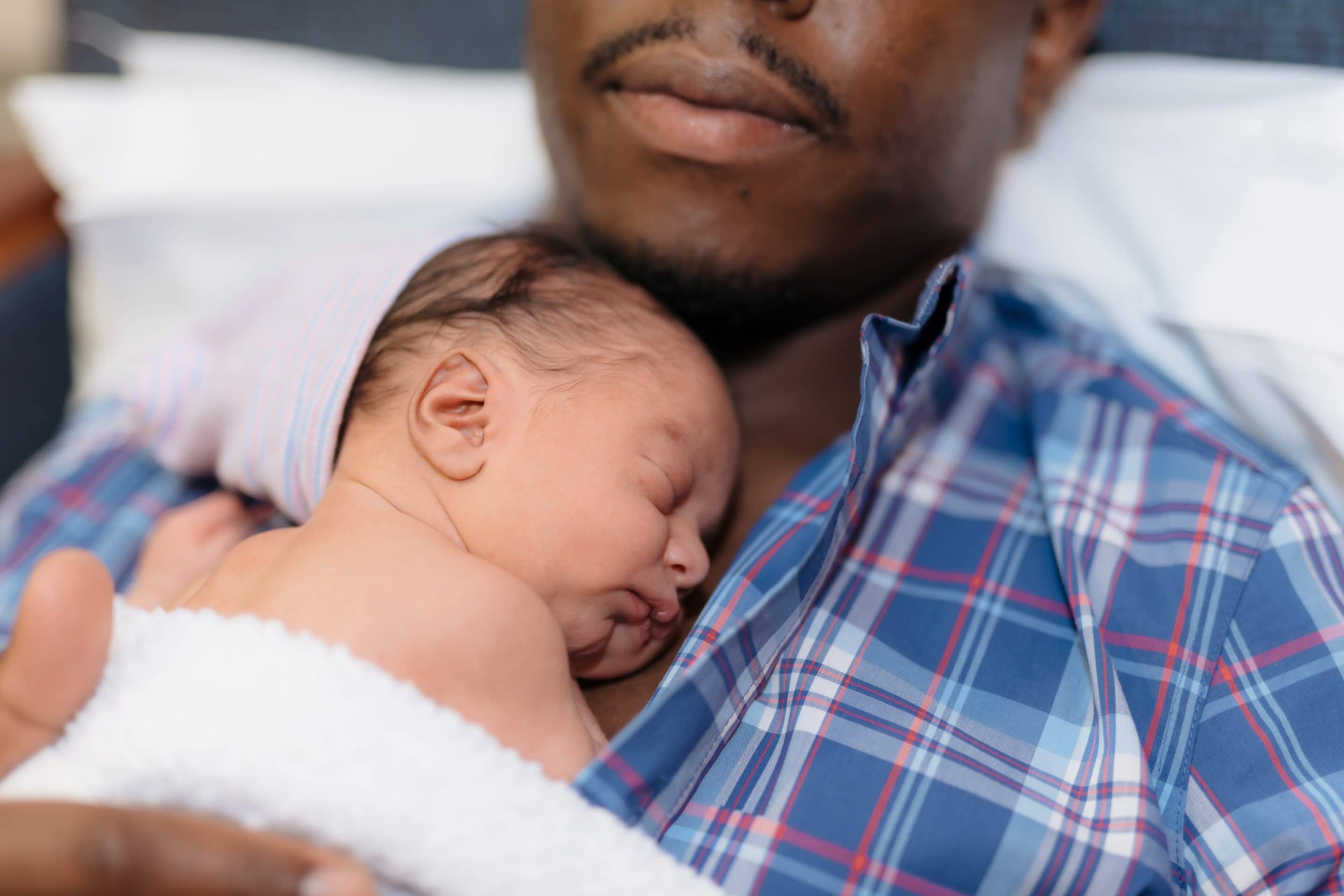 african american father with newborn son on his chest laying in hospital chair t20 yXopx9 scaled